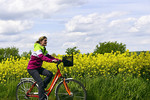 Junge Radlerin vor Rapsfeld