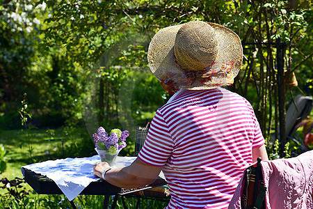 Frau am Gartentisch sitzend